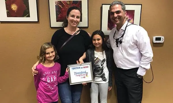 Dr. Okhovat with a patient family holding a prize from a practice raffle.